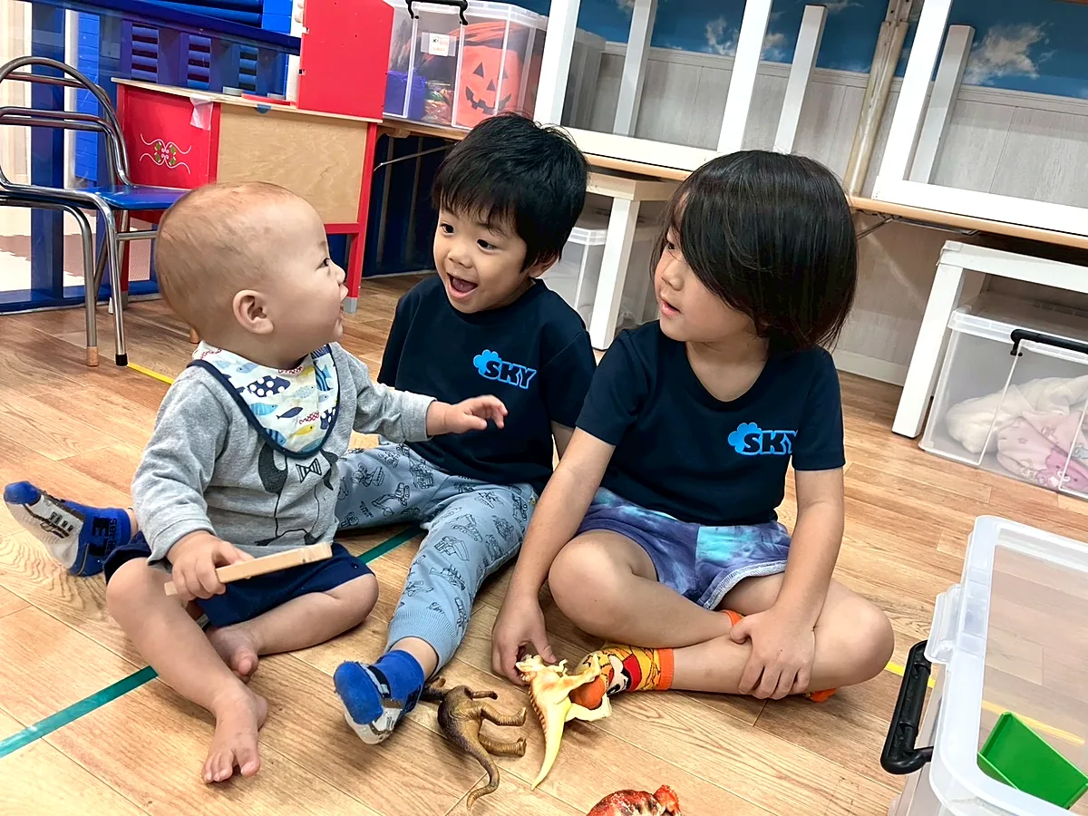室内で子どもたちが笑顔で関わり合っている様子