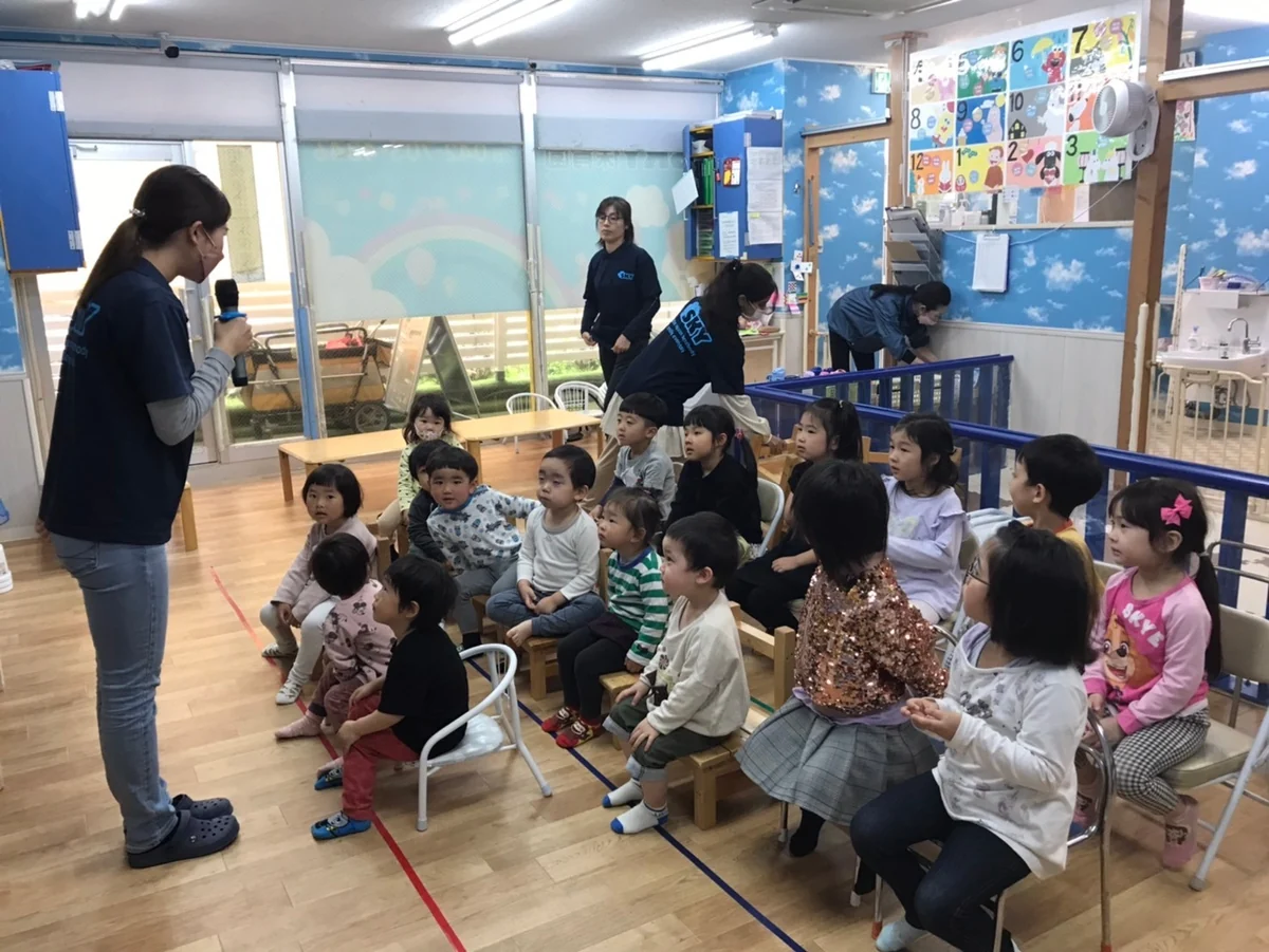 SKY保育園の教室で先生と子どもたちが集まって活動している様子