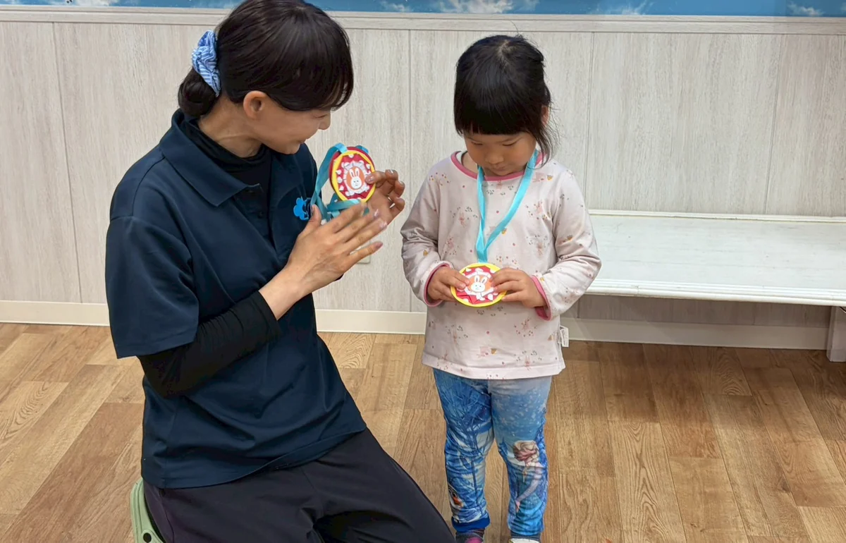 先生が子どもにメダルを見せながら励ましている様子