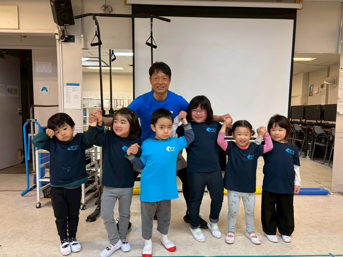 先生と子どもたちが手をつないで笑顔で過ごしている様子